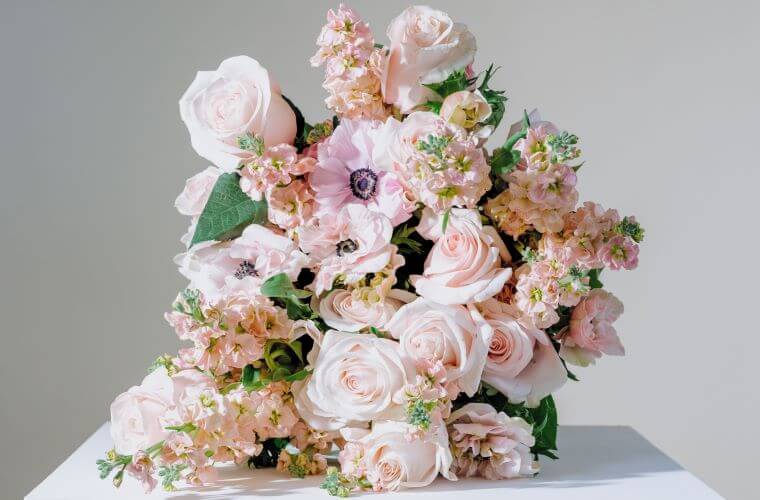 A pink and white bouquet of flowers including roses and anemones