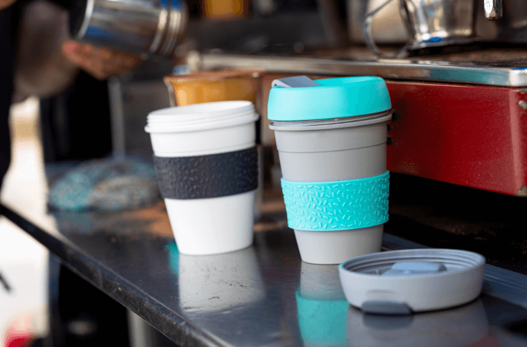 Two reusable cups on a metal shelf with a blurred background