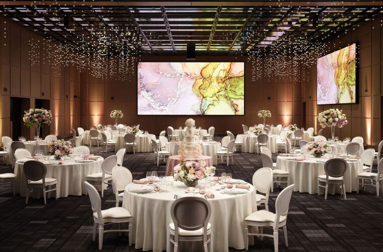 White tables and chairs set up for a wedding with pink and white flowers on the tables